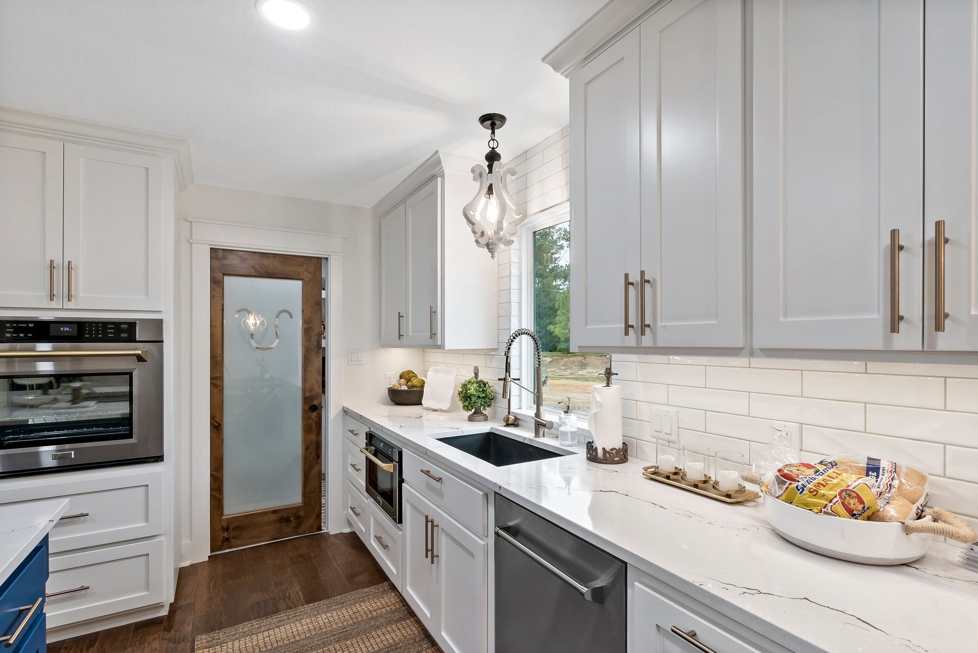 A kitchen with white cabinets , stainless steel appliances , a sink , and a bowl of food on the counter.