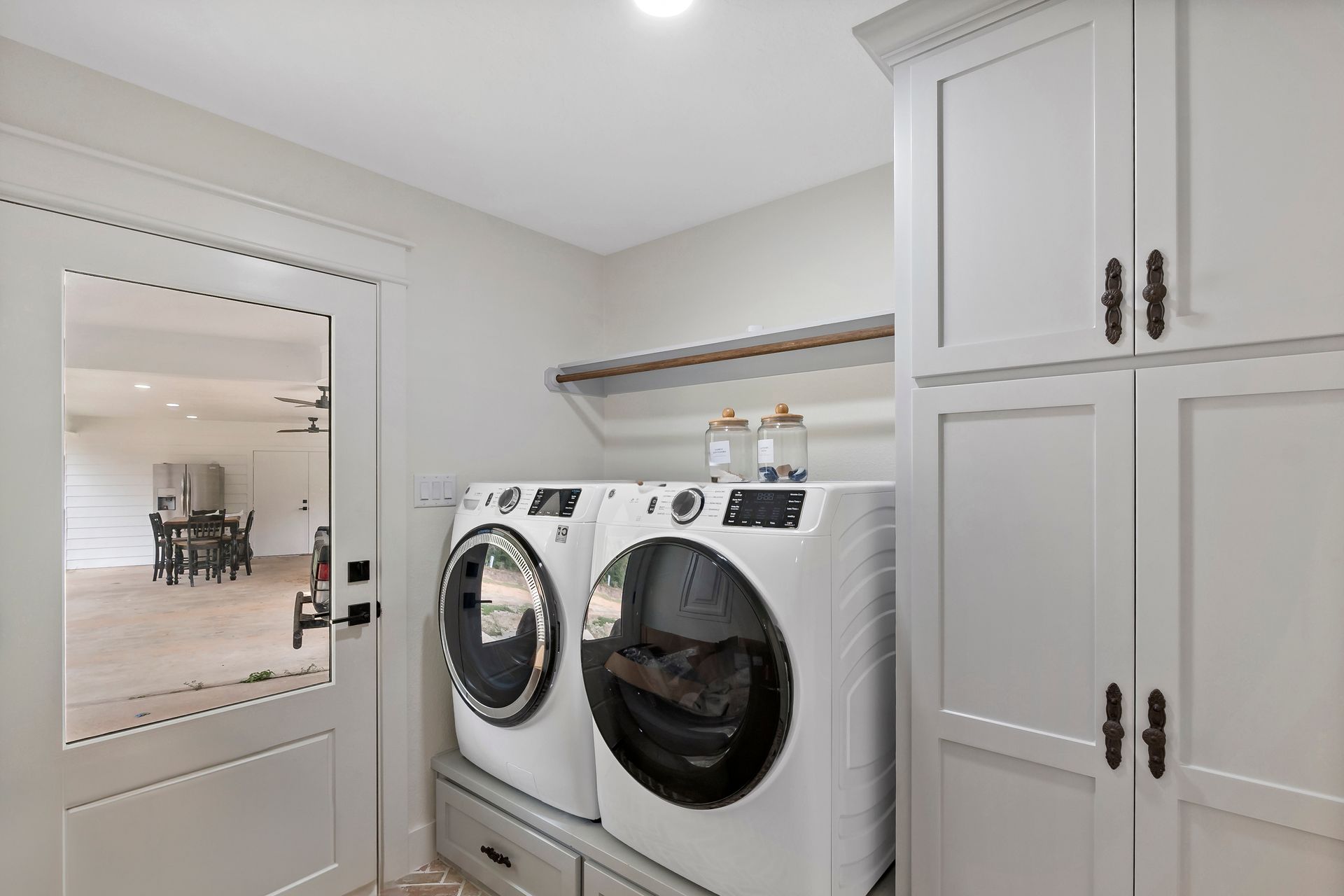 A laundry room with a washer and dryer and white cabinets.
