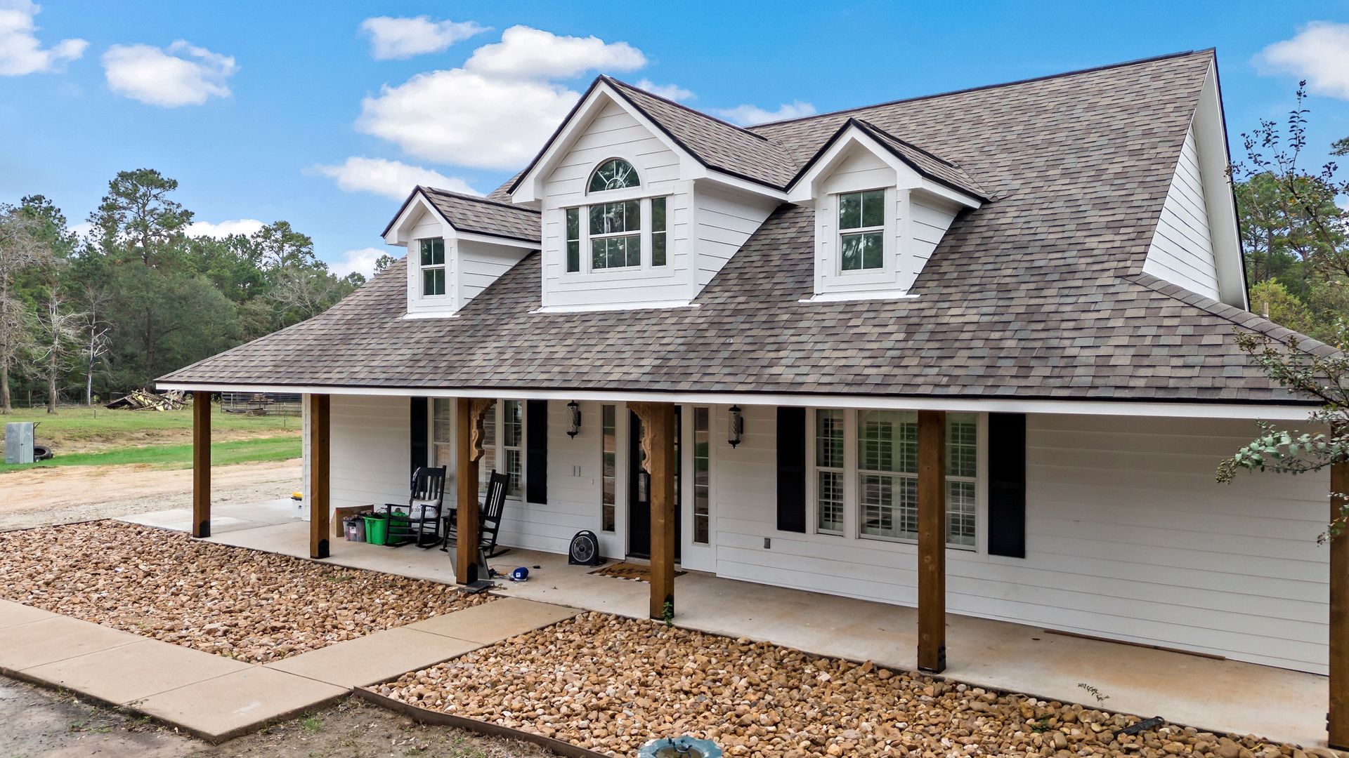 A large white house with a porch and a gray roof.