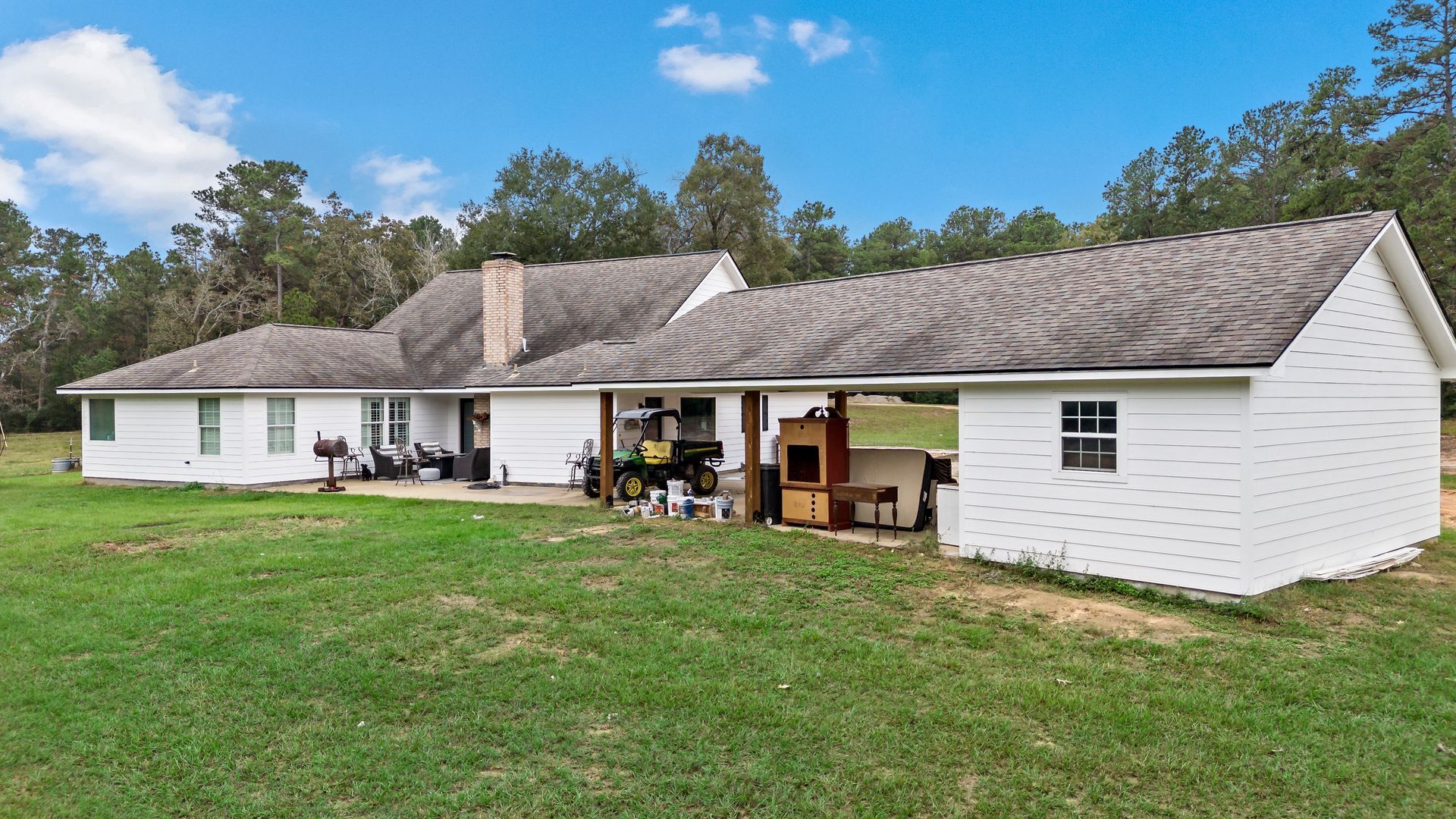 A large white house is sitting on top of a lush green field.