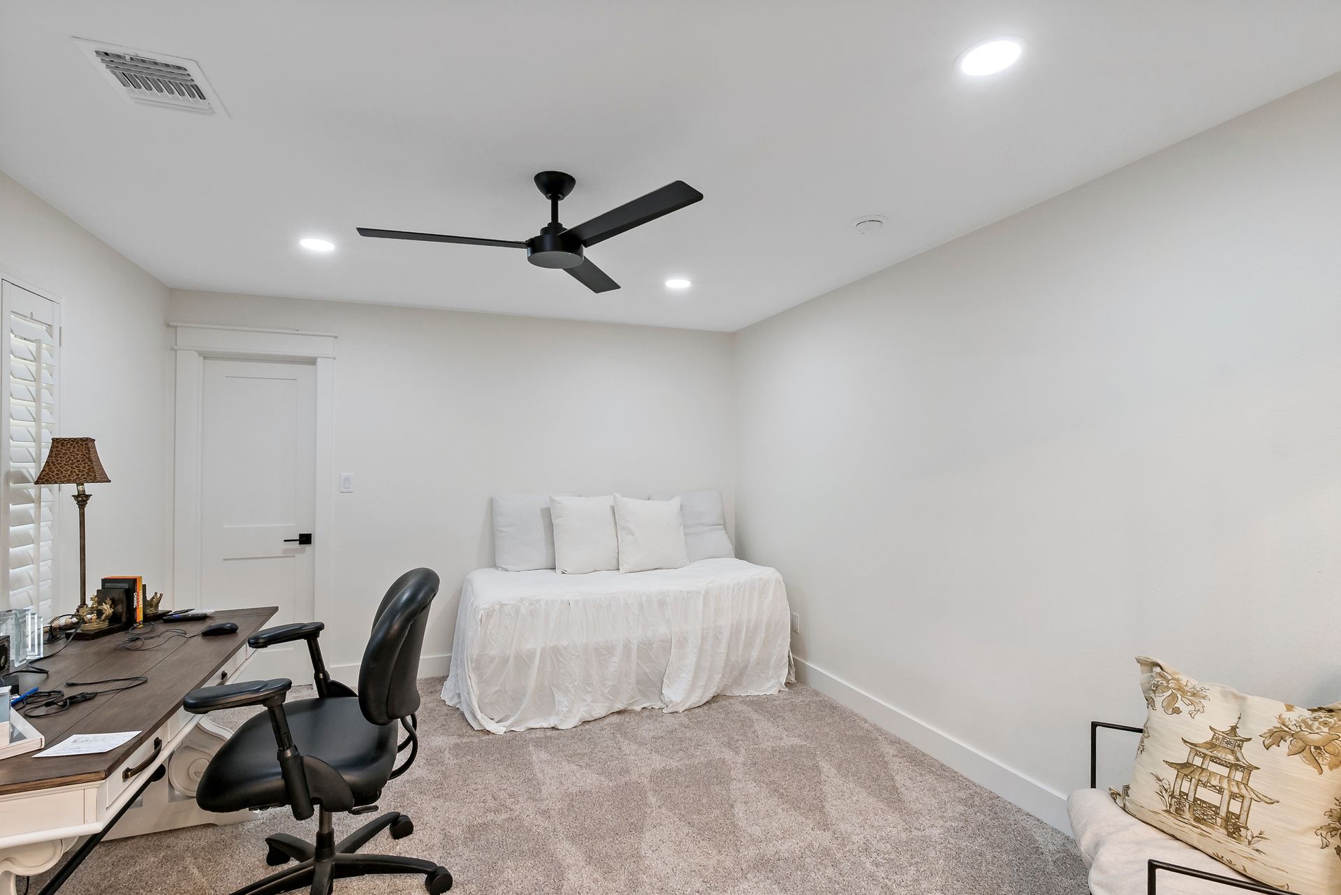 A bedroom with a bed , desk , chair and ceiling fan.