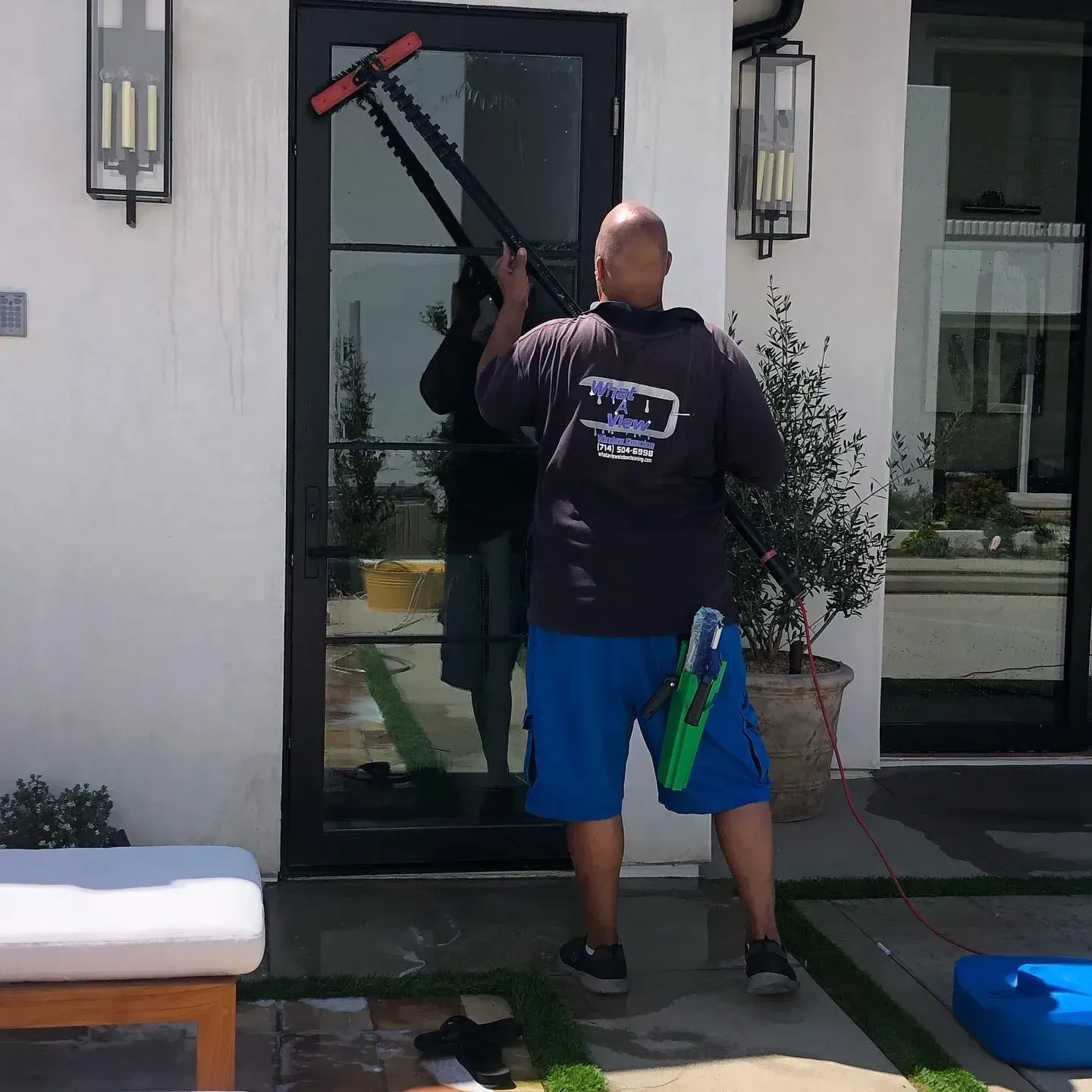 A man is cleaning a glass door with a brush
