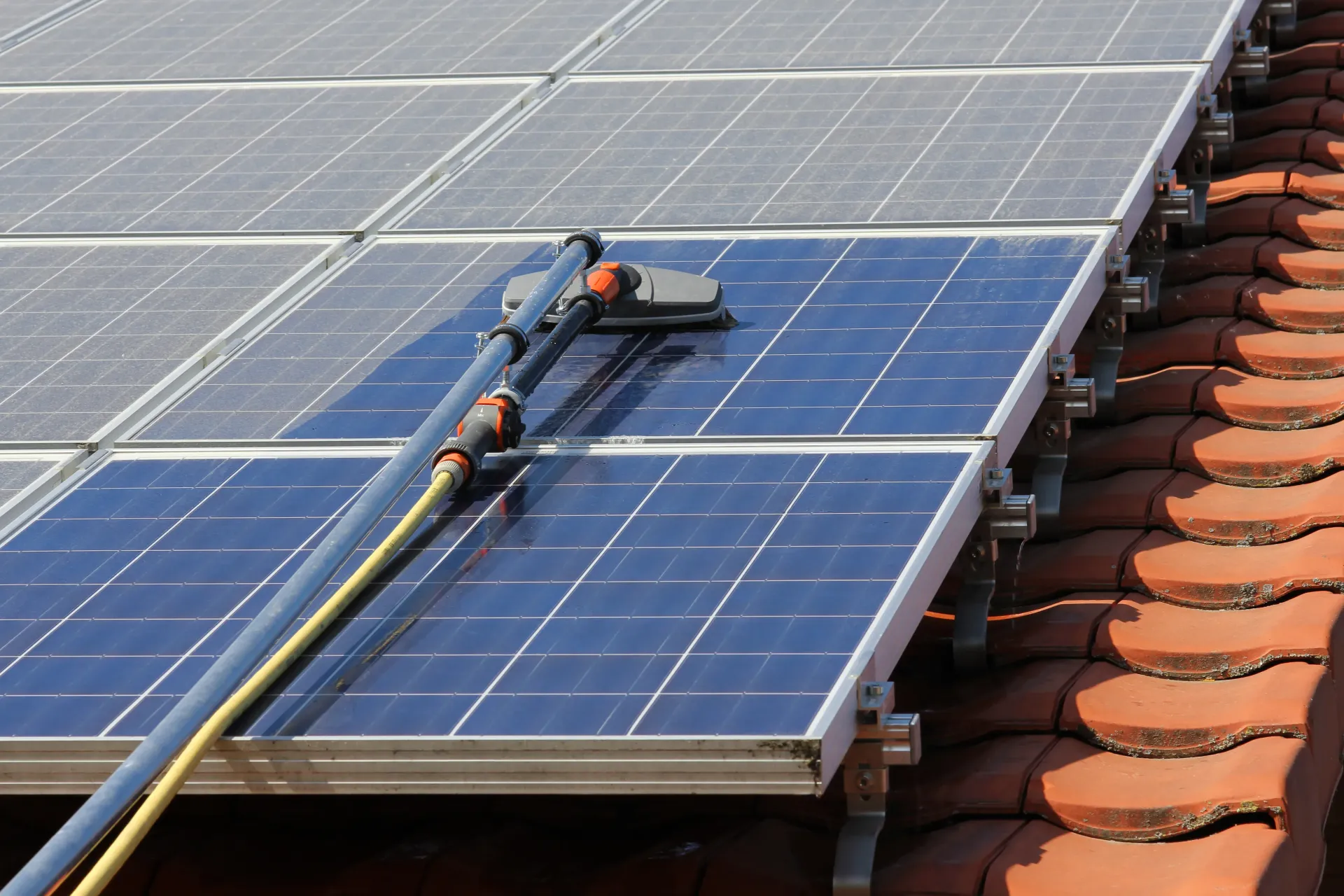 A person is cleaning solar panels on a roof