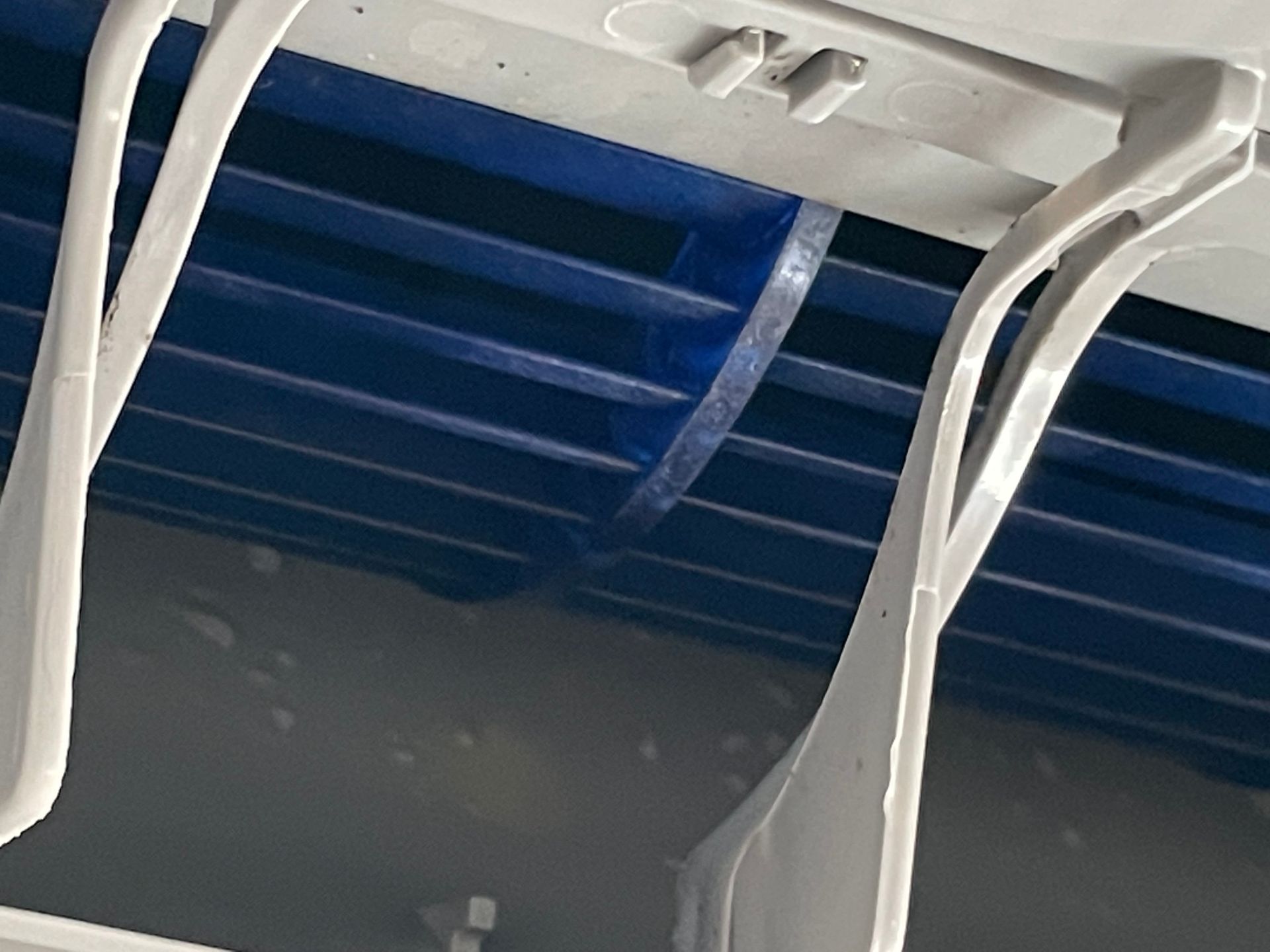 Close-up view of light gray plastic brackets against a blue-lined structure.