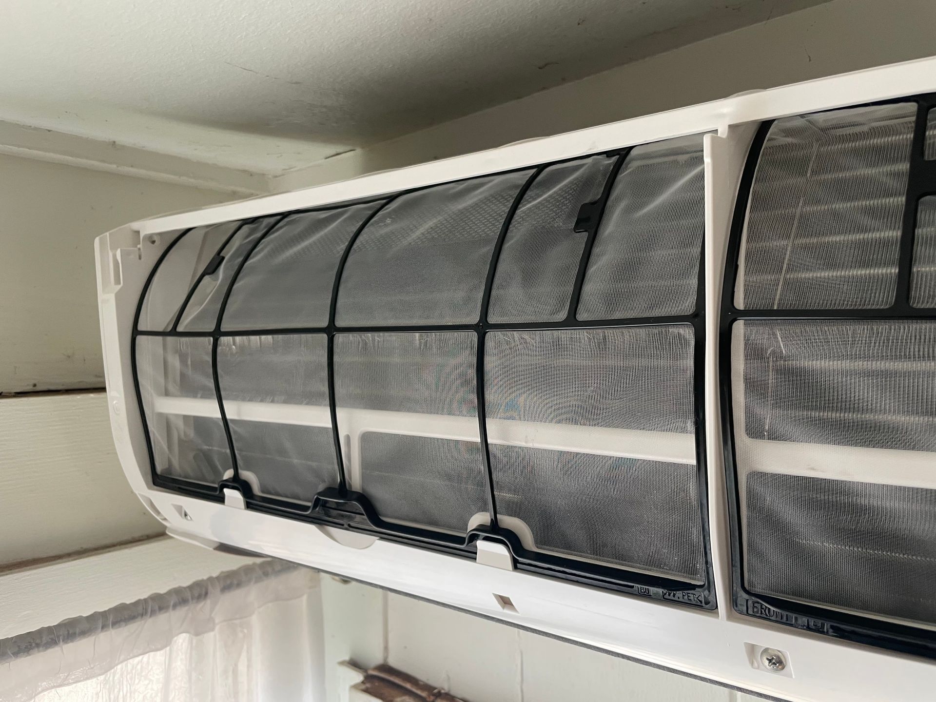 White wall-mounted air conditioner unit with visible black mesh air filters.