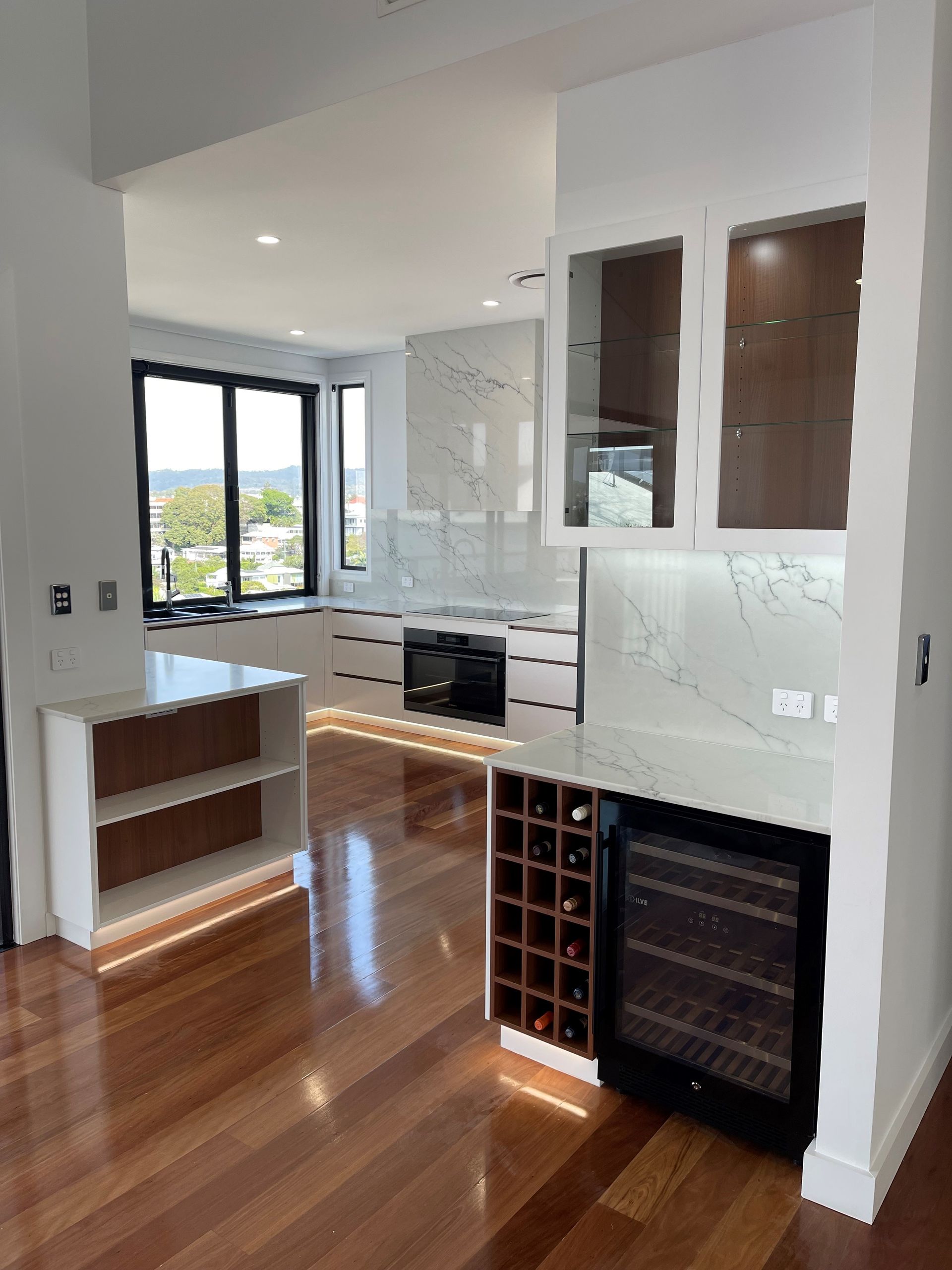 A kitchen with a wine cooler and a wine rack.