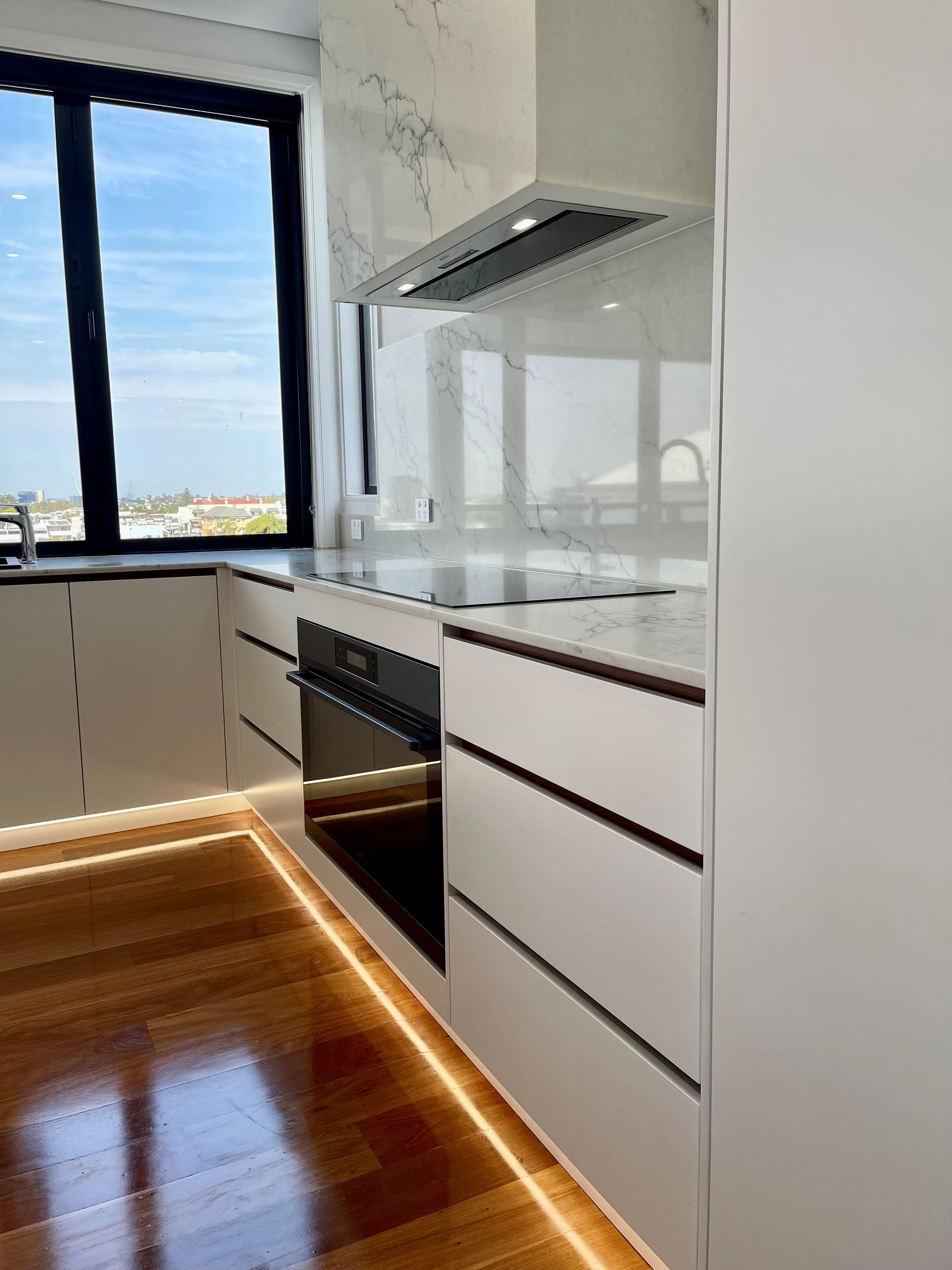 A kitchen with white cabinets , stainless steel appliances and a large window.