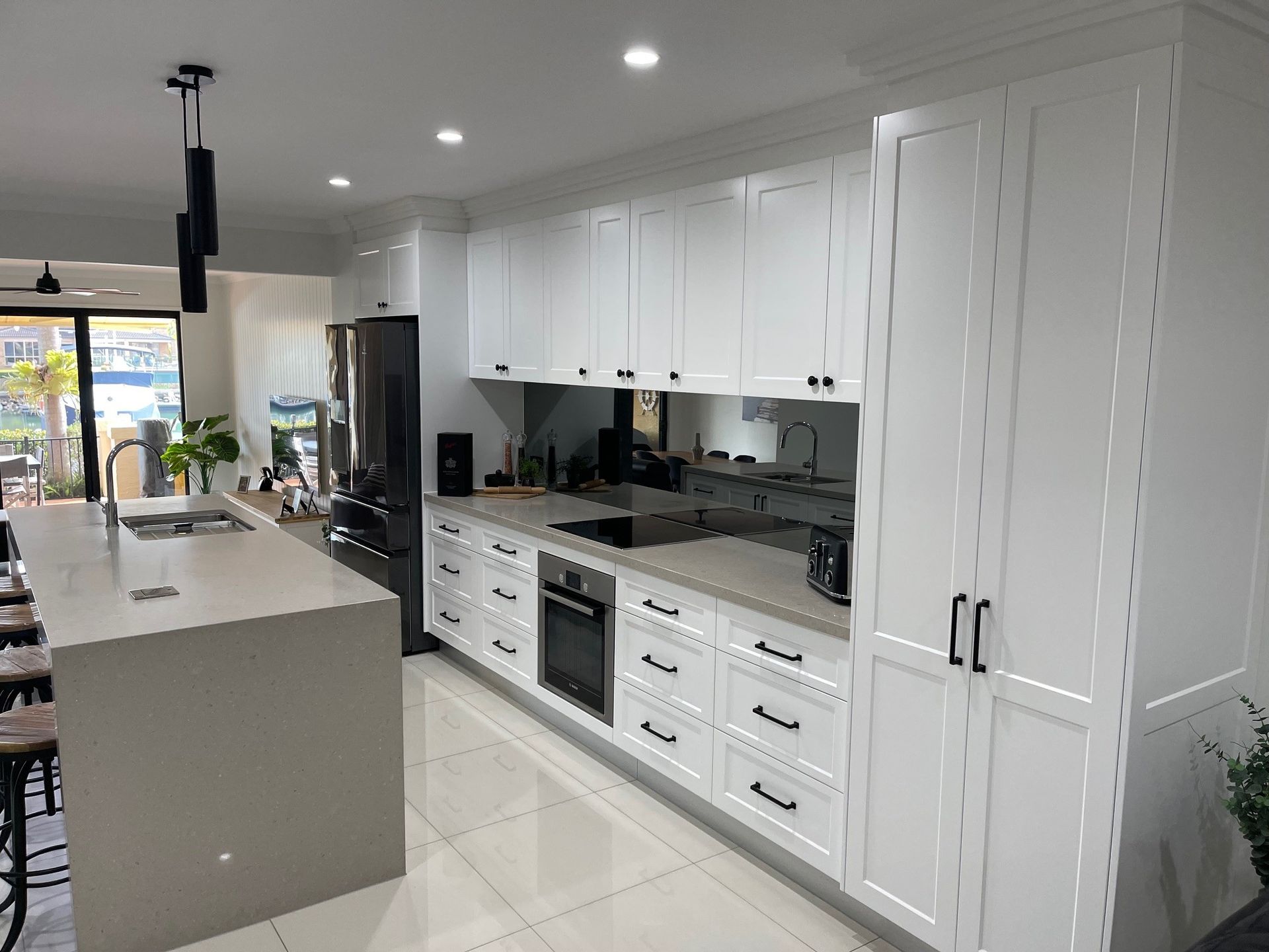 A kitchen with white cabinets , black appliances , and a large island.
