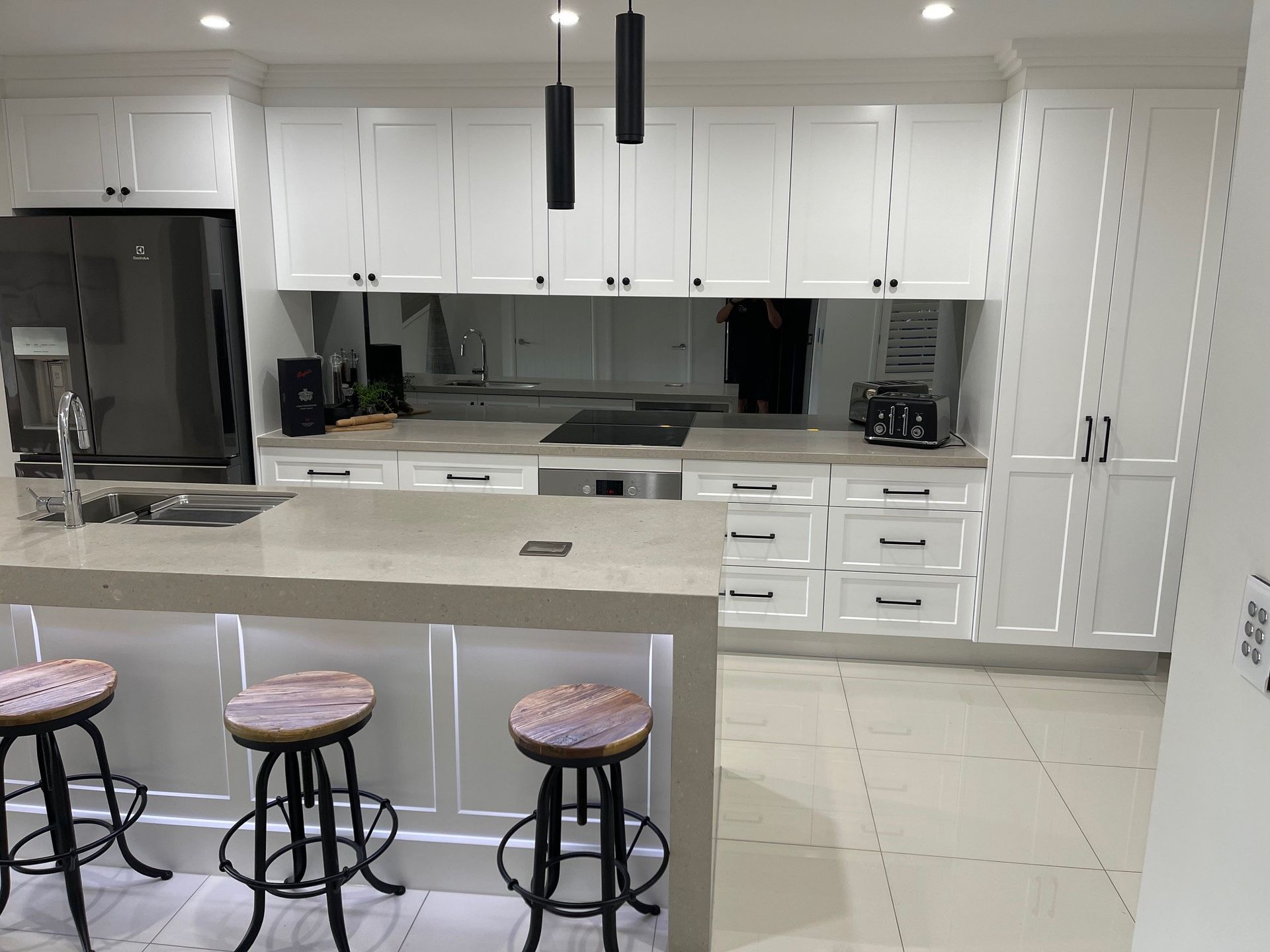A kitchen with white cabinets and stools and a large island.