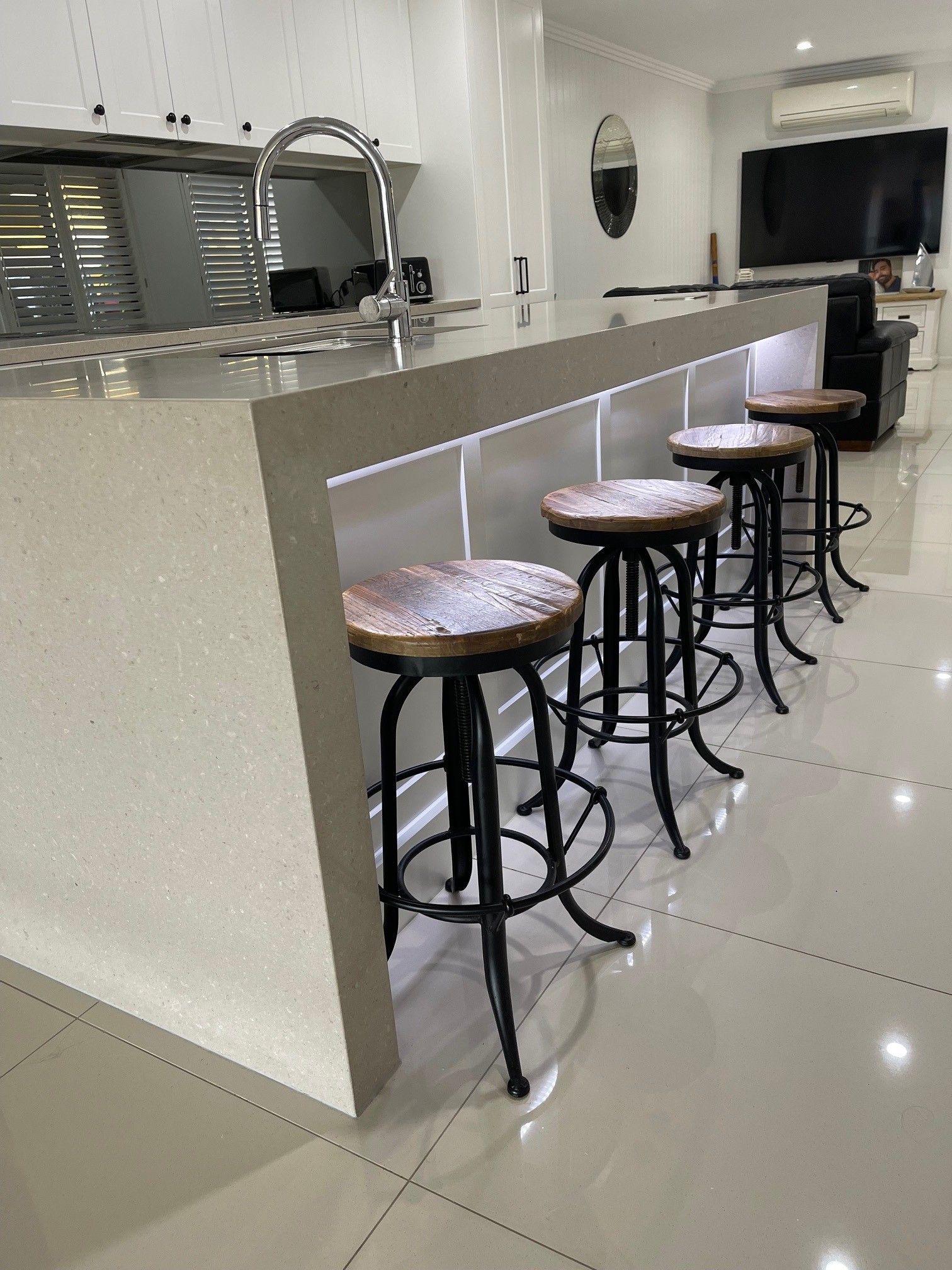 A kitchen with a row of bar stools sitting on top of a counter.