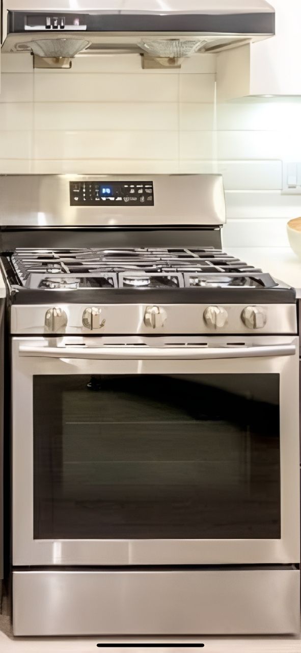 Hands testing an oven with a multimeter inside a kitchen