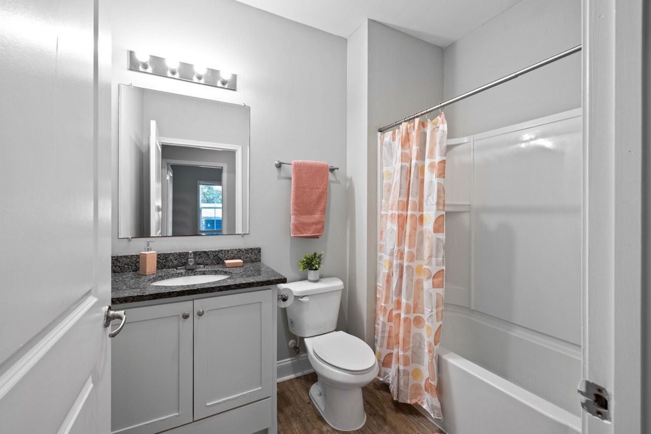 Apartment bathroom with vanity, sink, toilet, mirror, and tub/shower.
