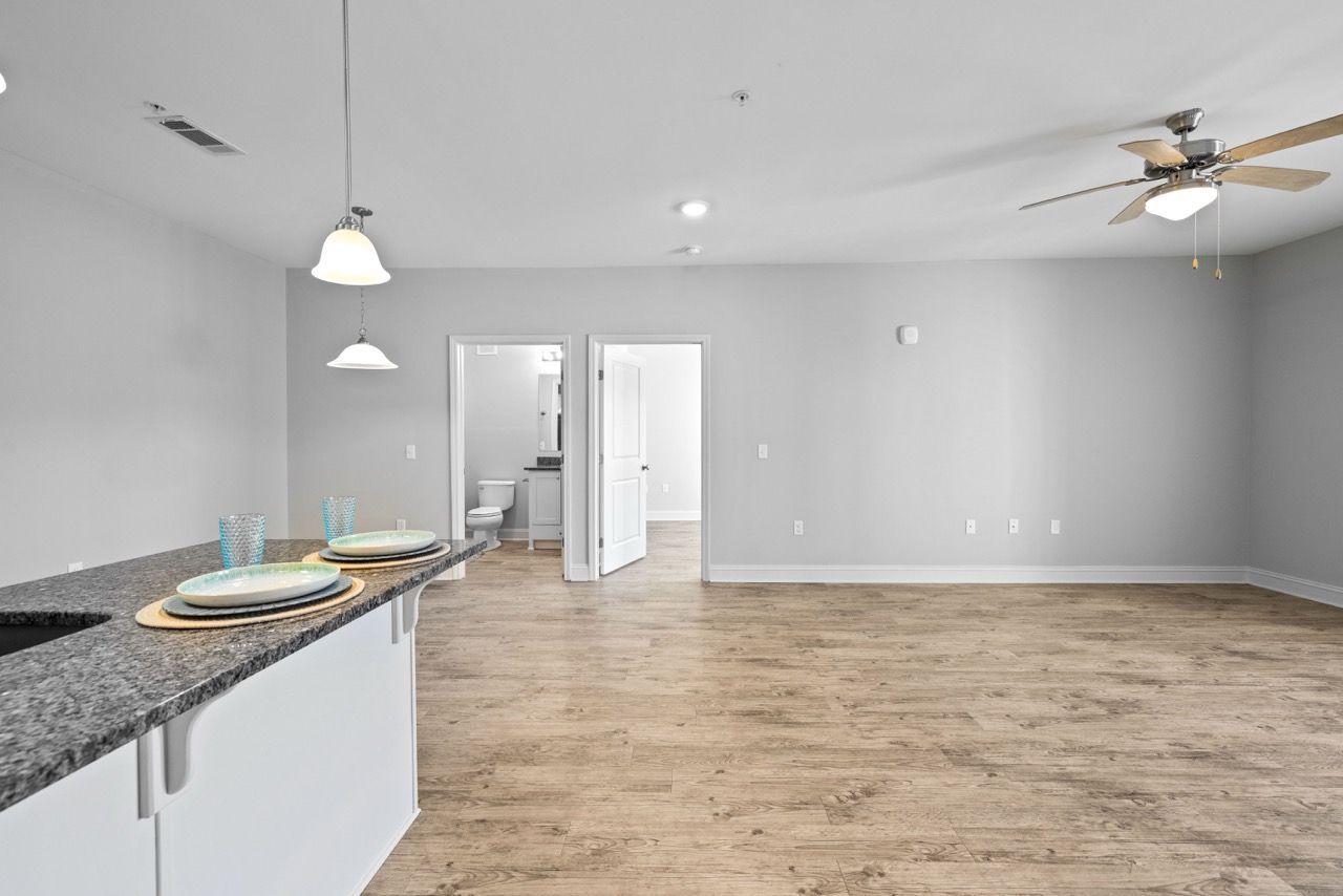 Open-concept living area with kitchen island, wood flooring, and doorway to bathroom.