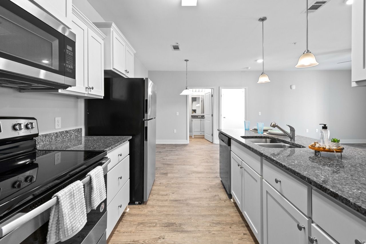 Modern kitchen in an apartment with granite countertops, stainless steel appliances, and an island.