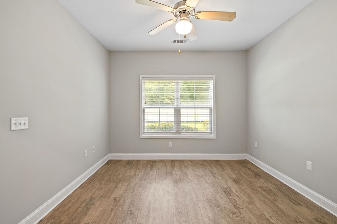 Empty bedroom with window, blinds, and ceiling fan.