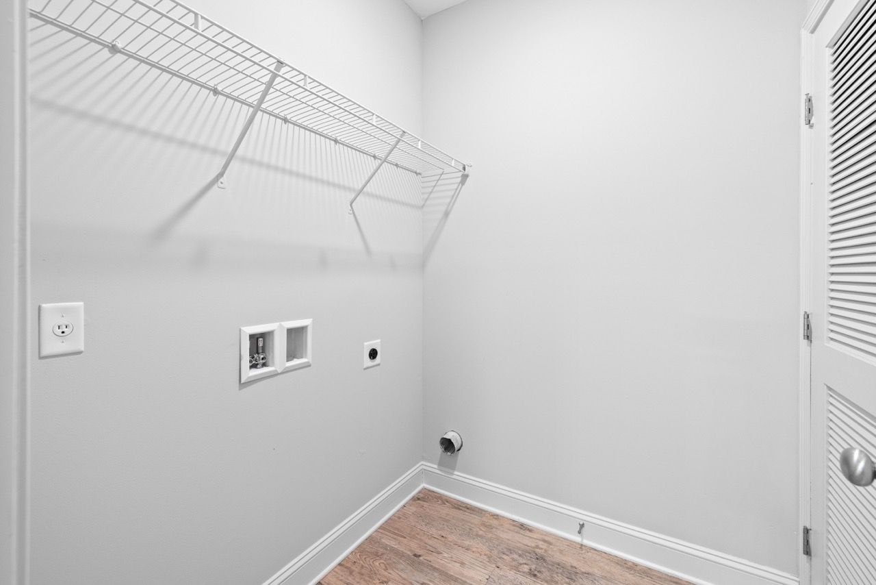 Laundry closet with washer/dryer hookups, water lines, drain, and a wire shelf.