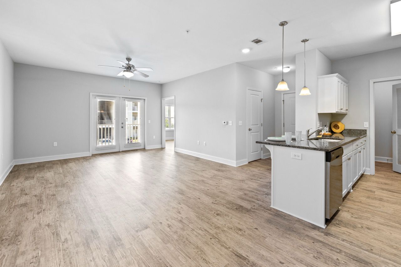 Open-concept living area with kitchen island, laminate flooring, and French doors to a balcony.