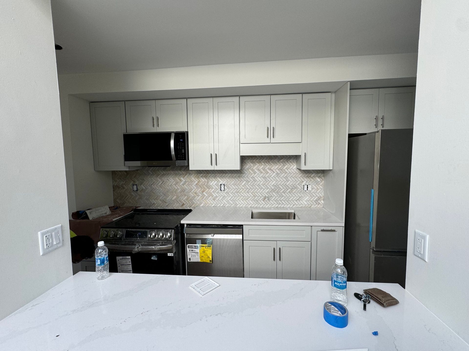 Newly renovated kitchen with gray cabinets, appliances, and backsplash.