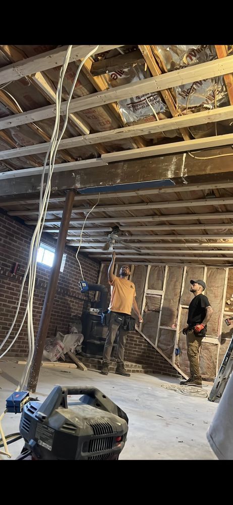 Construction workers in an unfinished room, working on the ceiling.