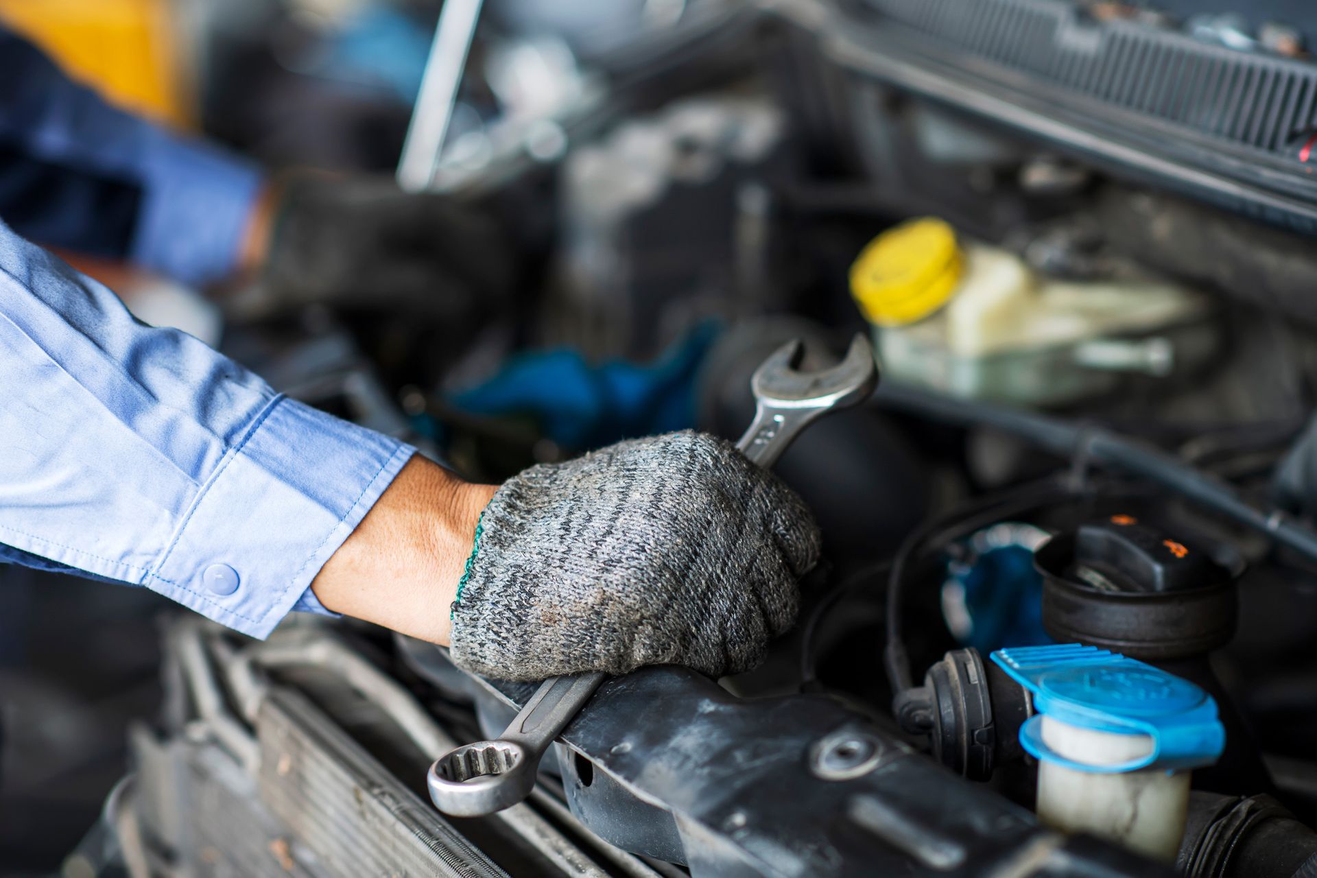 A man is working on a car engine with a wrench.