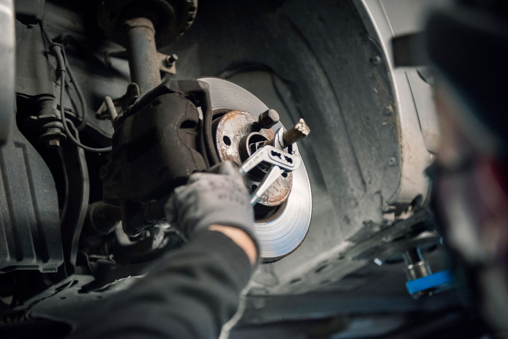 A man is working on a car wheel with a wrench.