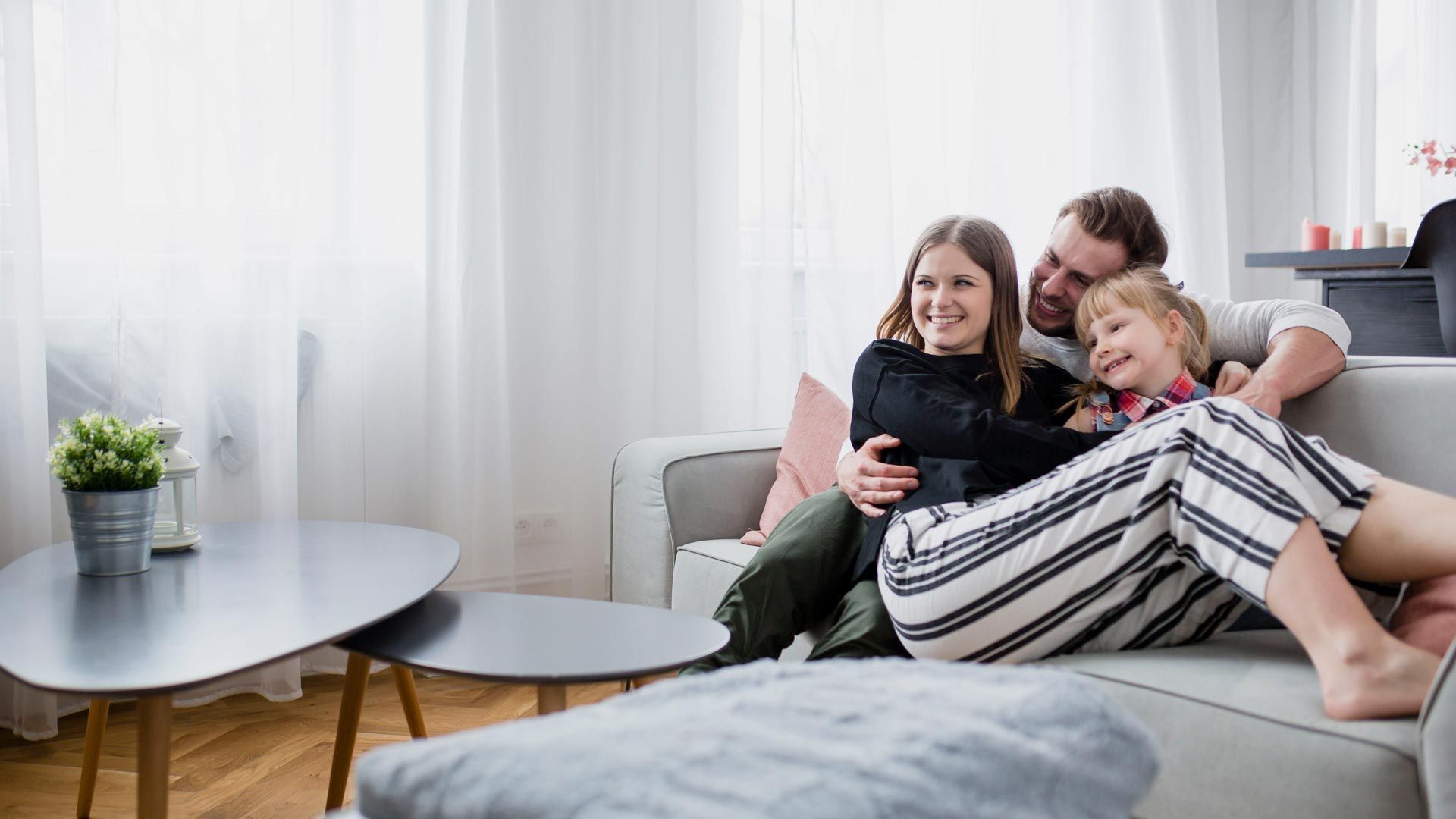 A family is sitting on a couch in a living room.