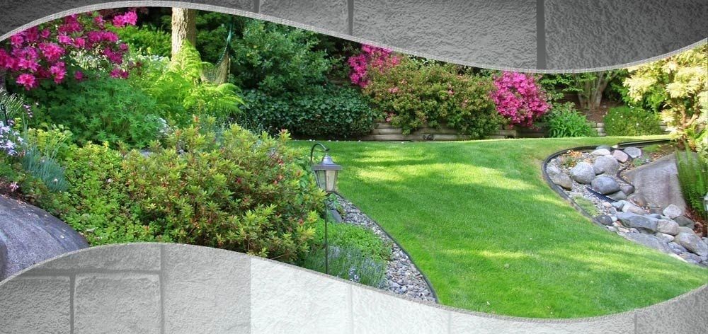 A lush garden with green lawn, shrubs, and pink flowers is framed by a gray border.