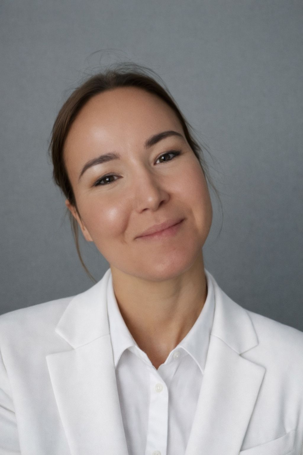 Cornelia Edinger, Eine Frau mit roten Haaren trägt ein weißes Hemd und lächelt. Expertin für kosmetische Behandlungen und Inhaberin von HalloSchönheit.