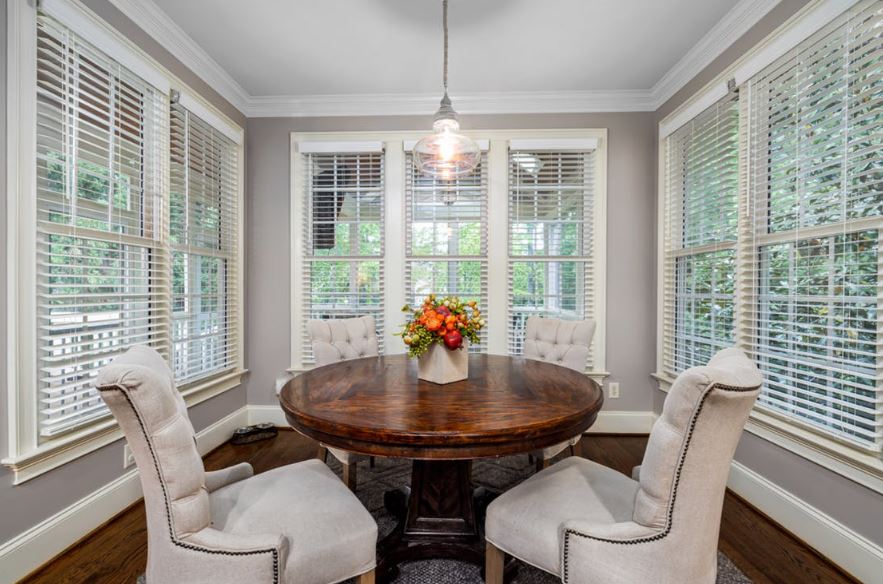 a dining room with a round table and chairs and lots of windows Love is Blinds Colorado services.