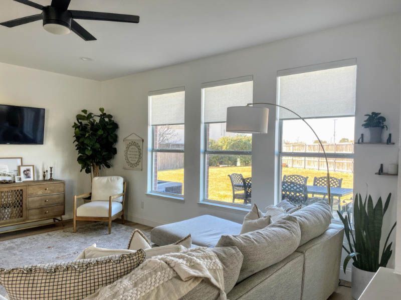 Love is Blinds CO: A living room with a couch , chair , television, and roller shades on 3 windows.