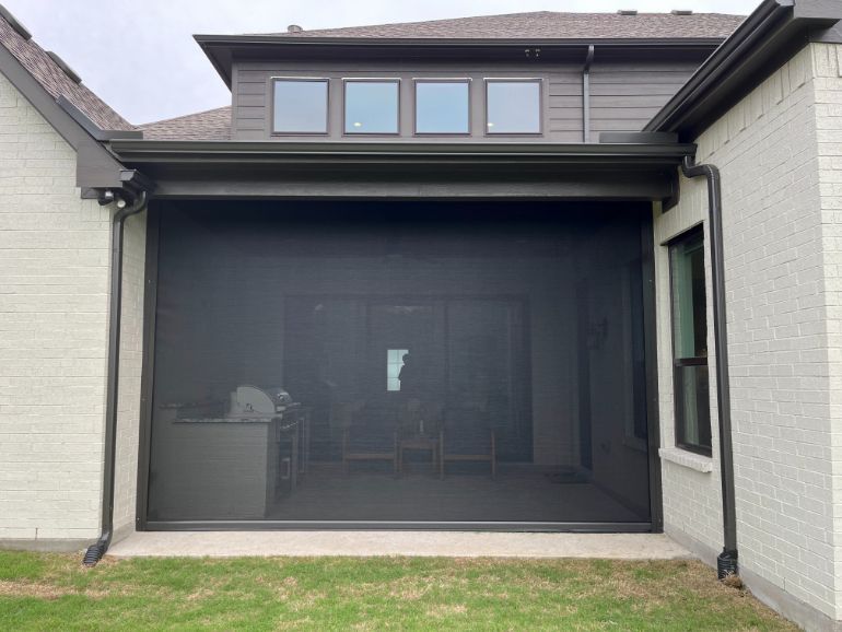 A grey home has an exterior patio shade to seclude its patio. 