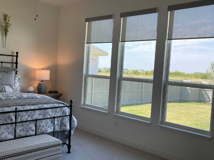 A bedroom with a bed , lamps , and three windows with cordless shades.