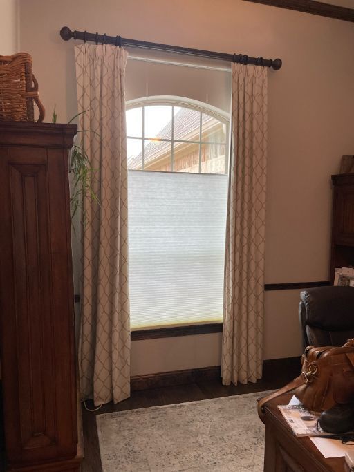 A living room with a large window and honeycomb shades.