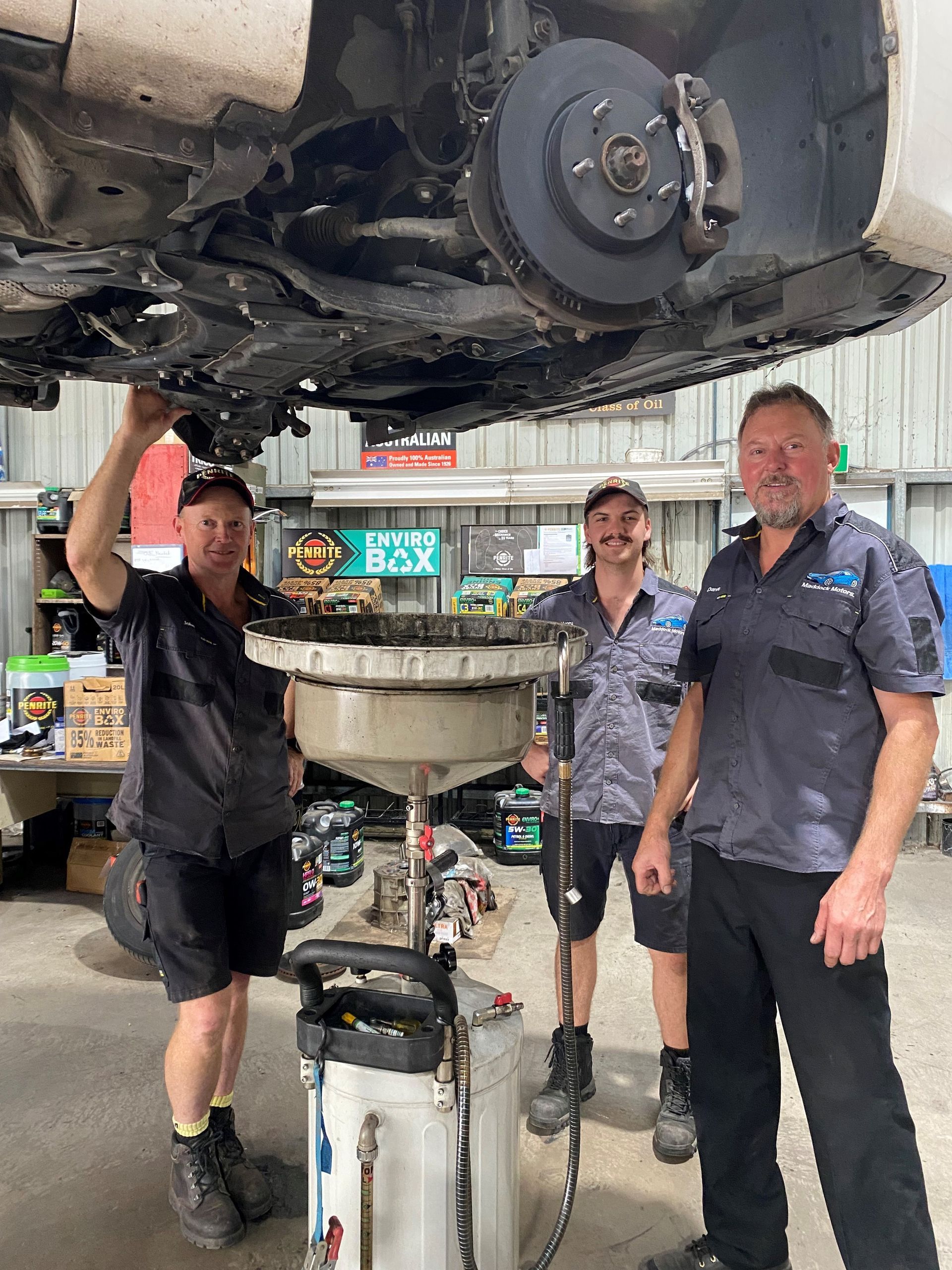 Three Car Mechanics Standing Under a Vehicle on Hoist — Auto Air Conditioning in Wodonga, VIC