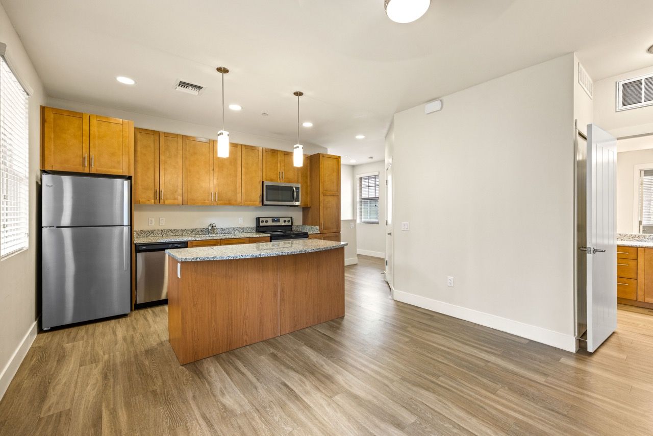 Open-concept kitchen with wood cabinets, granite countertops, island, and stainless-steel appliances.