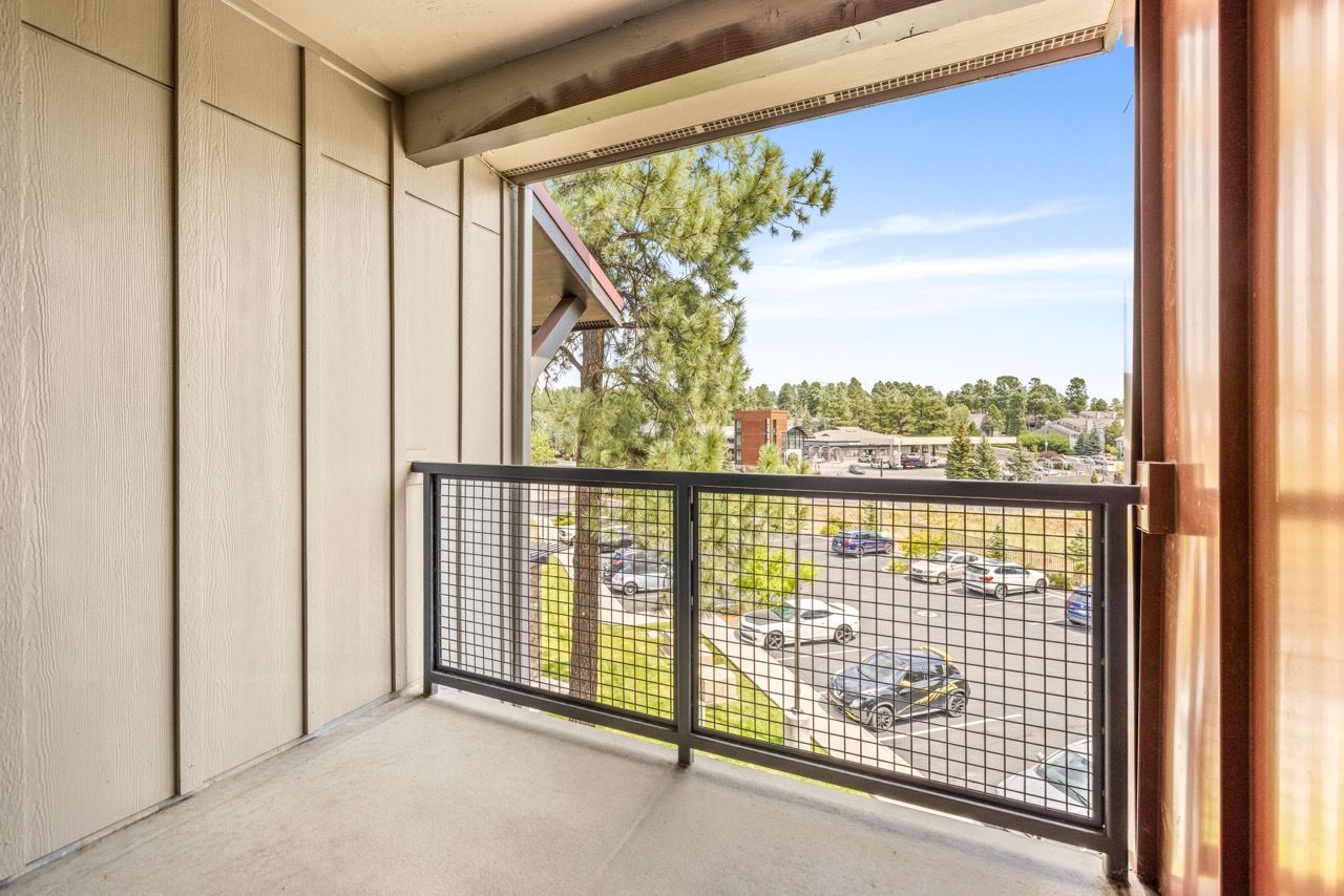 Balcony with beige siding and a black metal railing, overlooking a parking lot.