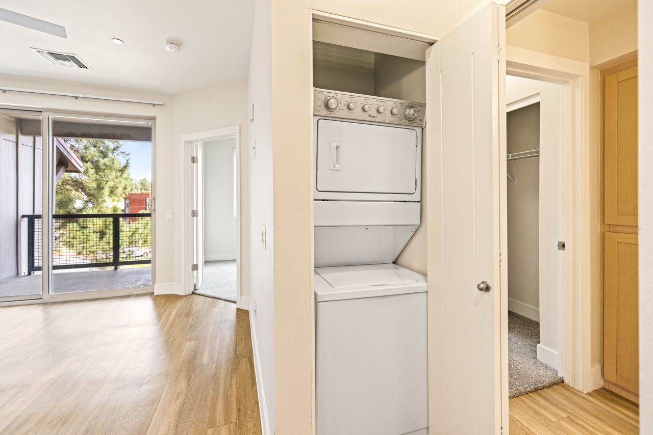 Stacked washer and dryer in a laundry alcove inside an apartment.