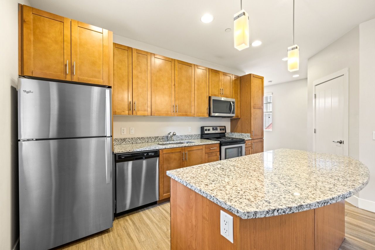 Modern apartment kitchen with granite countertops, stainless steel appliances, and a large island.