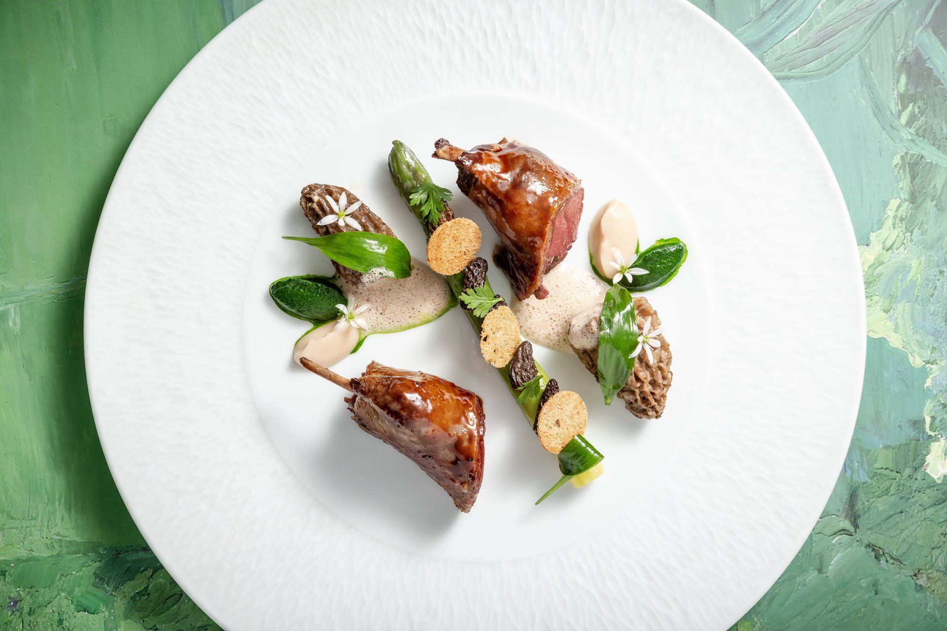 Une assiette blanche garnie de viande et de légumes sur une table verte.