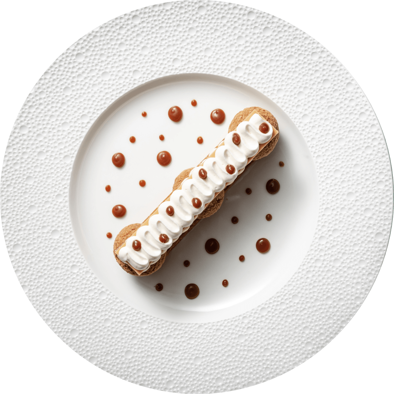 Une assiette blanche garnie d'un dessert à la crème fouettée et sauce caramel.