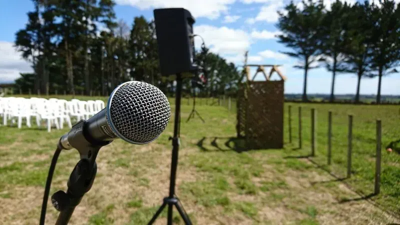 A microphone is sitting on a tripod in a field.