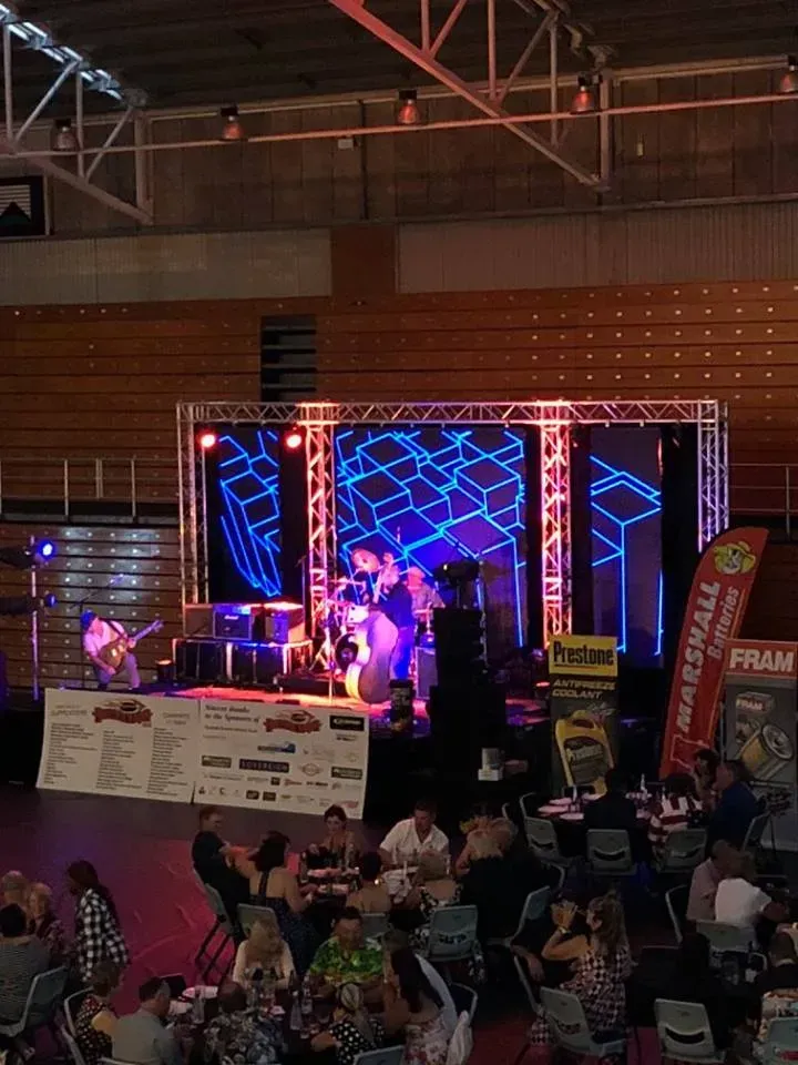 A group of people are sitting at tables in front of a stage