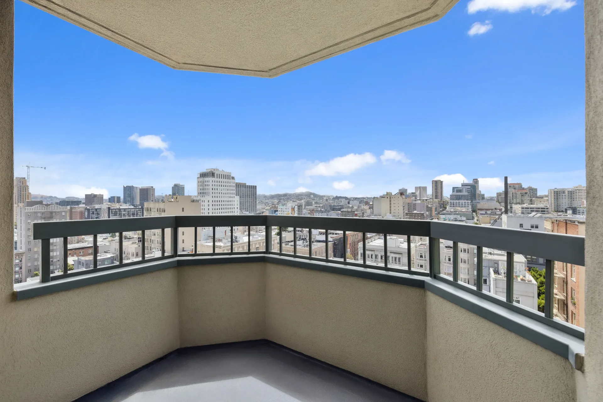 Balcony with railing overlooking a city skyline and blue sky.