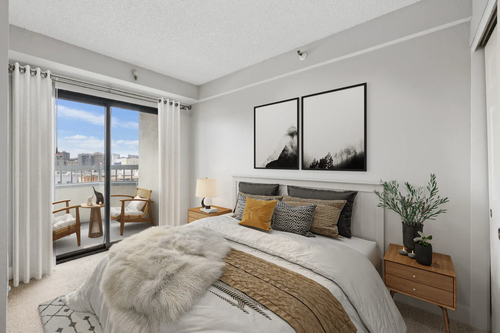 Bedroom with a white bed, gray accents, and sliding glass doors to a balcony.