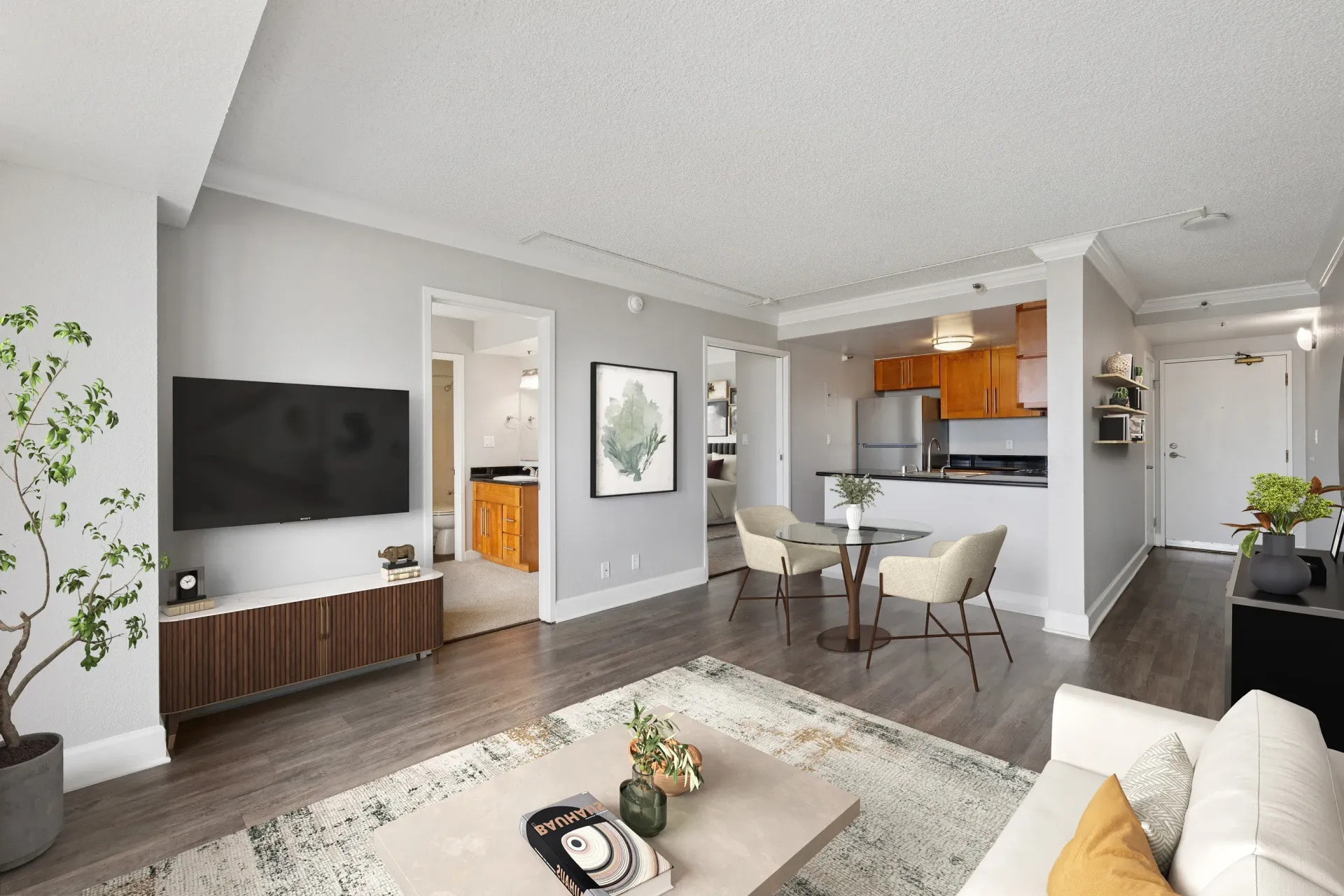Open-concept living room with TV, dining table, and a kitchen in a modern apartment.