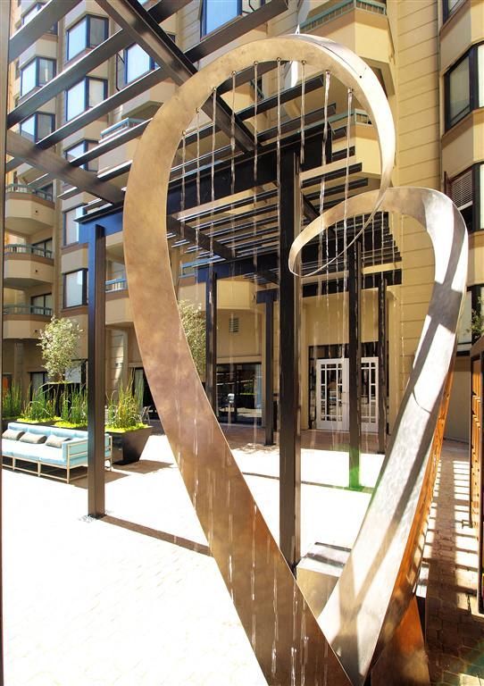 Outdoor courtyard with an abstract metal sculpture near the building entrance.