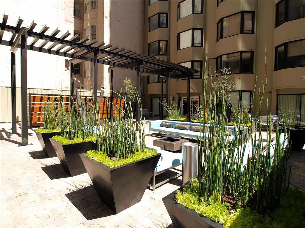Outdoor apartment community courtyard with modern seating, planters, and a pergola.