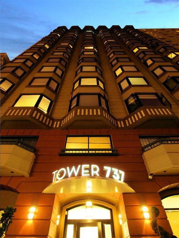 Tall apartment building exterior at dusk with illuminated Tower 731 sign.