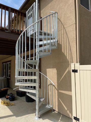 A spiral staircase is sitting on the side of a house.