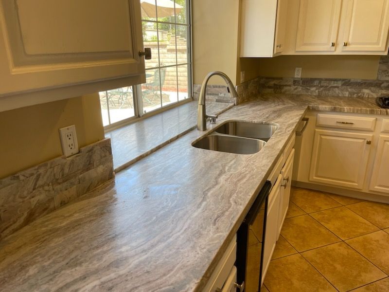 A kitchen with a sink , cabinets , and a window.